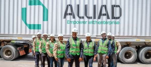 A team of Alliad employees gathered in front of a cargo truck, representing teamwork and logistics services.